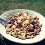 Salade de pâtes de sarrasin au thon dans un saladier blanc posé sur l'herbe dans le jardin