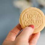 Comment booster l'énergie de ses enfants avec ces 5 goûters sains pour l'école ? Main tenant un petit-beurre fourré à la pâte d'amande au sucre de coco de face