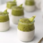 Verrines de panna cotta au lait de coco surmontées d'une purée de kiwi, servies dans des pots en verre sur fond blanc