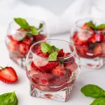 Salade de fraises légère et fraîche : recette facile et rapide pour l'été 3 verrines remplies de salades de fraises et basilic sur fond blanc. Quelques fraises et feuilles de basilic tout autour