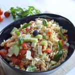 Salade de pâtes froide avec assaisonnement feta, tomates, concombre et basilic frais dans un saladier bleu foncé