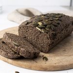 Pain graine de chia protéiné sans farine tranché sur une planche en bois ronde